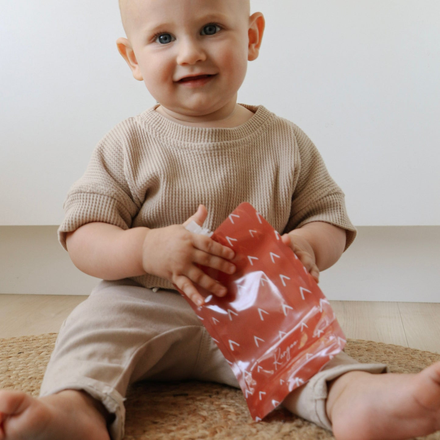 Pochette à compote réutilisable Kangoo rouge dans les mains d'un bébé