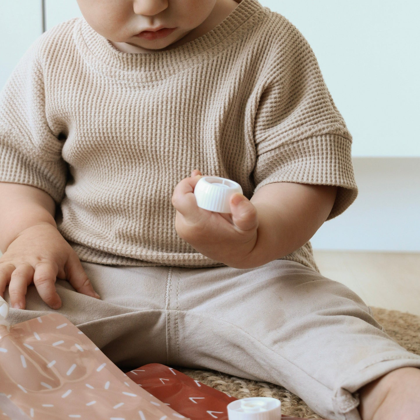 un bébé tient un bouchon en plastique blanc