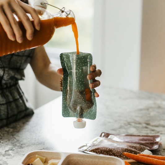 Pochette à compote réutilisable Kangoo verte avec une mère qui verse du smoothie